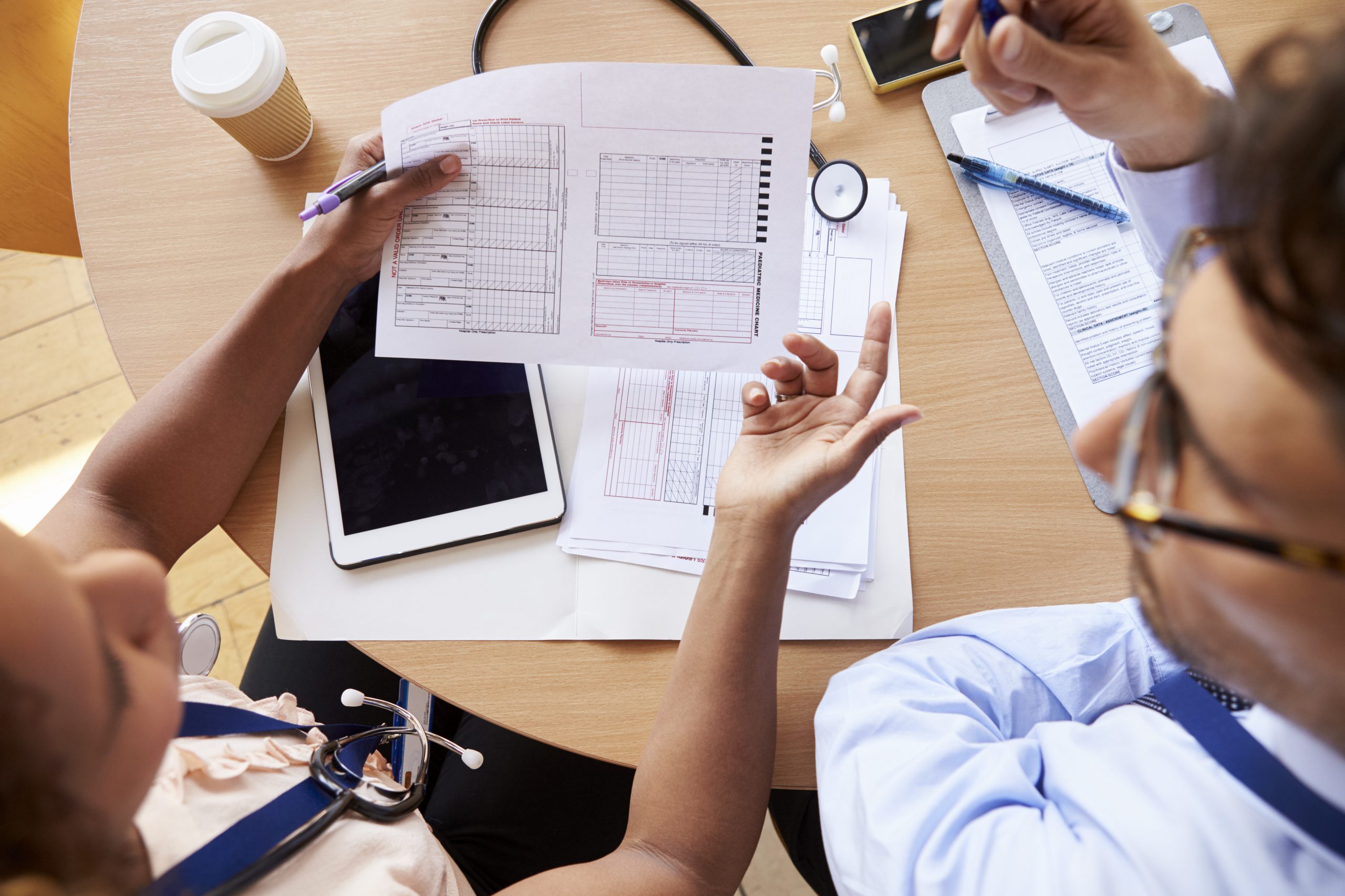 Overhead shot of doctors in consultation over member notes developing medical blueprint and plan