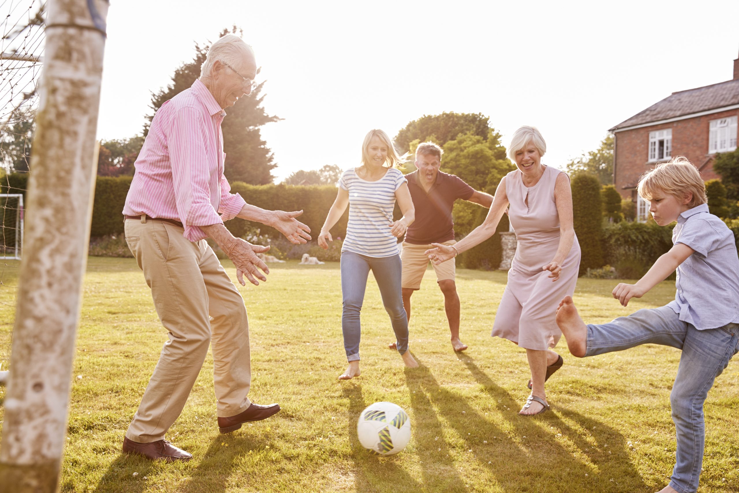 Multi generation family playing football in the garden longevity through medicine 3.0